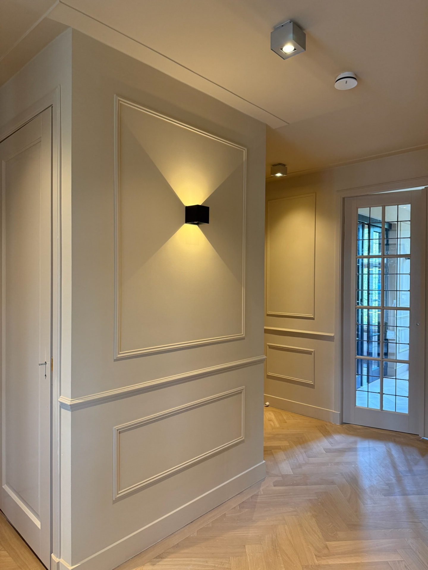 Wanddetail met sierlijst, spiegel en wandverlichting